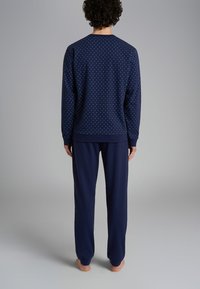 Felpa navy con pois blu chiaro, colletto a girocollo, polsini a coste, abbinata a pantaloni navy a tinta unita con vita elastica.