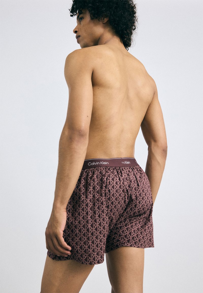 Bordo bokseri ar ģeometrisku rakstu, elastīgu jostu ar "Calvin Klein" zīmolu un mīkstu auduma tekstūru.