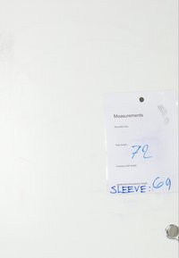 Měření štítku na bílém pozadí; štítek obsahuje velikost ramene, celkovou délku (72), délku šatů a délku rukávu (69), vše ručně psané.