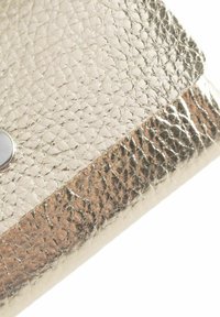 Metallic gold clutch with a textured pattern, featuring a circular silver snap closure and a smooth bottom edge.