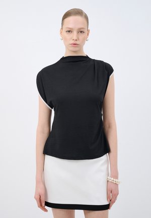 Haut noir à manches courtes avec un col haut et un ourlet arrondi, associé à une jupe blanche avec un liseré noir. Texture de tissu douce et lisse.