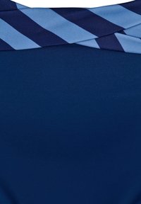 Jūras zila auduma virsma ar horizontālu zilu un tumši zilu svītru dizainu augšpusē. Gluda tekstūra, ar apņemjo izskatu pie kakla.