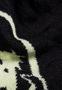 Tessuto in maglia caratterizzato da una base nera con un design verde chiaro a contrasto; texture morbida con una combinazione di fili lisci e pelosi.