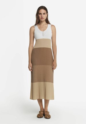 Robe maxi sans manches en tricot avec un décolleté en V, présentant un design bicolore en blanc, beige et marron, avec une texture côtelée.