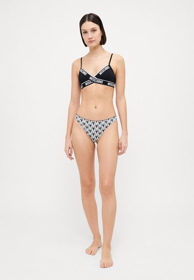 Black bralette with cross straps featuring white "Moschino" branding; high-waisted bikini bottom in black and white geometric pattern.