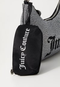 Svart och silver klutchväska med en yta prydd med rhinestones, försedd med en svart tygpouch märkt "Juicy Couture" i silverbokstäver.
