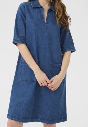 Spijkerjurk in donkeblaauw met een kraag, korte mouwen en twee zakken aan de voorkant. Heeft contrasterende stiksels en een losse pasvorm.