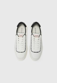 Hvite sneakers med svarte detaljer, tekstiloverdel, snøring, signaturlogo detalj og strukturert såle for godt grep.