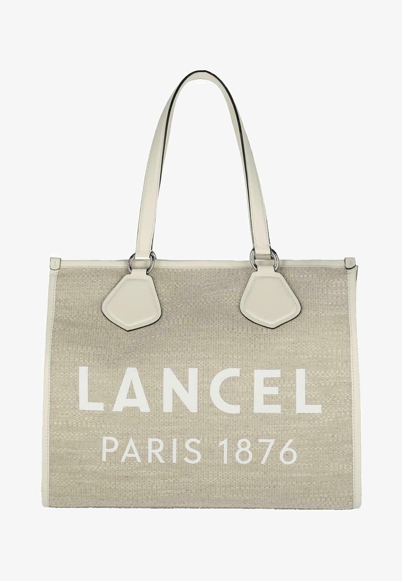 Sac beige avec le logo "LANCEL PARIS 1876" en blanc, fabriqué à partir de matériau tissé. Présente deux longues poignées et des accents en cuir sur les côtés.