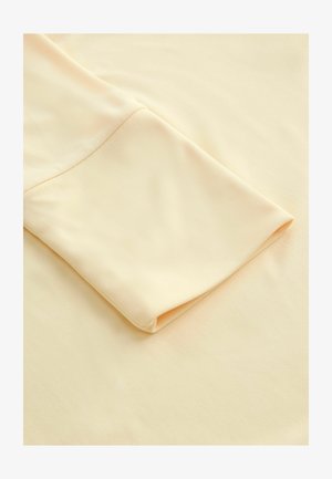 Helebeežiline kangas volditud varrukaga, mis näitab sujuvat tekstuuri ja pehmet välimust, rõhutades selle lihtsust ja elegantsi.