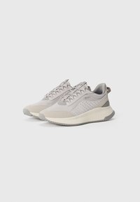 Hellgraue sportliche Sneakers mit Mesh- und synthetischen Überzügen, texturiertem Boden, abgerundeter Zehenpartie, Schnürung vorne und perforierter Seite für Atmungsaktivität.