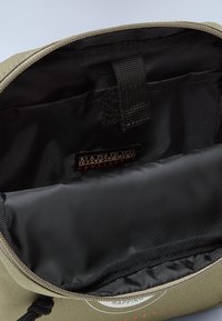 Borsa verde oliva con zip, con un interno liscio e foderato in nero, dotata di spallacci regolabili e etichetta con logo all'interno.