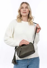 Olivově zelená kožená crossbody taška se zipem, akcentem v podobě střapce a nastavitelným popruhem; obdélníkový tvar s hladkým povrchem.