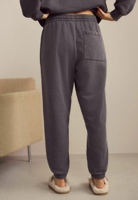 Šedé joggingové kalhoty z měkkého materiálu, s elastickým pasem a jednou zadní kapsou. Návrh se zakončením na kotnících pro dobře padnoucí vzhled.