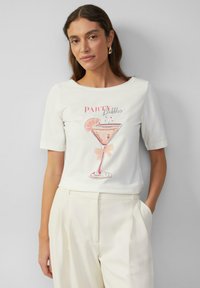 Witte t-shirt met korte mouwen, voorzien van een roze cocktailafbeelding en de tekst "PARTY Bubbles". Glad materiaal, ontspannen pasvorm en ronde halslijn.