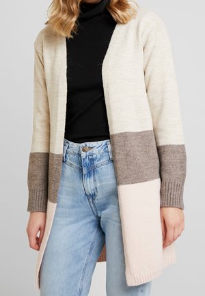 Beige, hnědý a světlý růžový cardigan s barevnými bloky, s žebrovanými manžetami, otevřeným předním designem a měkkou pletenou strukturou. Nosený přes černý top.