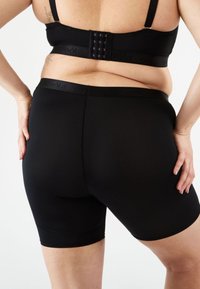 Musta korkeavyötäröinen shortsit, jotka on valmistettu venyvistä materiaaleista. Sisältää sileän vyötärönauhan, jossa on logo, ja on muotoiltu istuvaksi.