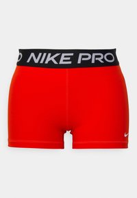 Pantalones cortos de rendimiento Nike Pro rojos con una cintura elástica negra que presenta "NIKE PRO" en texto blanco y un pequeño logotipo blanco en la parte delantera.