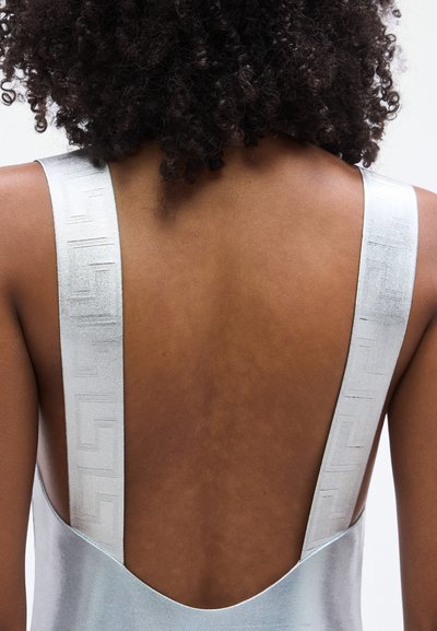 Φόρεμα χωρίς μανίκια και ύφασμα σε μεταλλικό ανοιχτό γαλάζιο. Διαθέτει φαρδιές τιράντες με διακοσμητικό σχέδιο. Λείο υφή, μινιμαλιστικός σχεδιασμός.