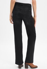 Sorte denim jeans med rett ben, baklommer, subtil tekstur og mid-rise midjebånd, kombinert med brune ankelstøvletter med hæl.