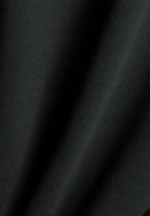 Tissu noir présentant une texture lisse avec une structure de tricot visible, exhibant un tombé doux et une légère brillance sous la lumière.
