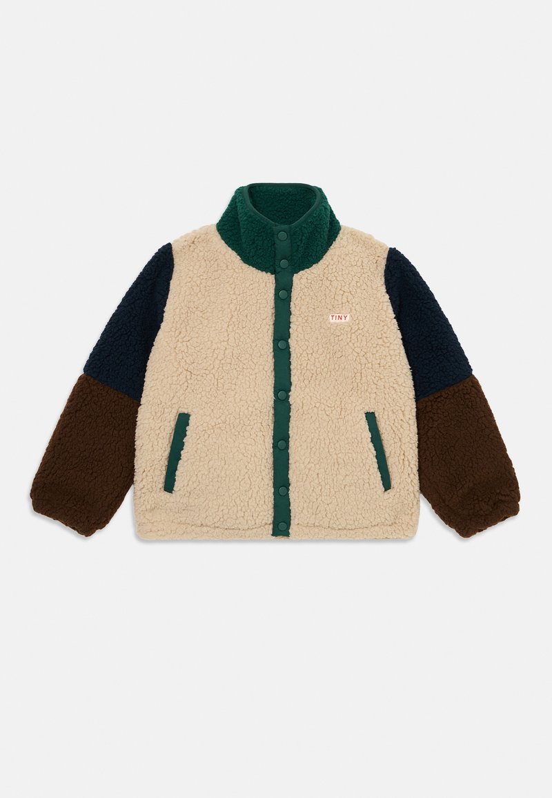 Veste en polaire beige, marine et marron avec des finitions vertes, des boutons-pression, deux poches et une étiquette "TINY" sur la poitrine gauche.