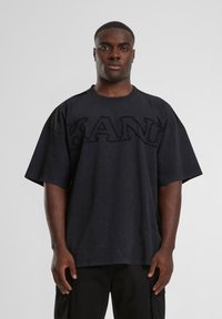 Melna pārmērīga t-krekls ar strukturētu "KANYE" logo. Īsas piedurknes, apaļa dekoltē un mīksts kokvilnas materiāls. Vienkāršs un mūsdienīgs dizains.