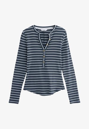 Navy un balta svītrota garām piedurknēm blūze ar pogājamu kātiņu, ribota tekstūra un noapaļota apakšmala. Priekšpusē ir četri zelta tonēti pogas.