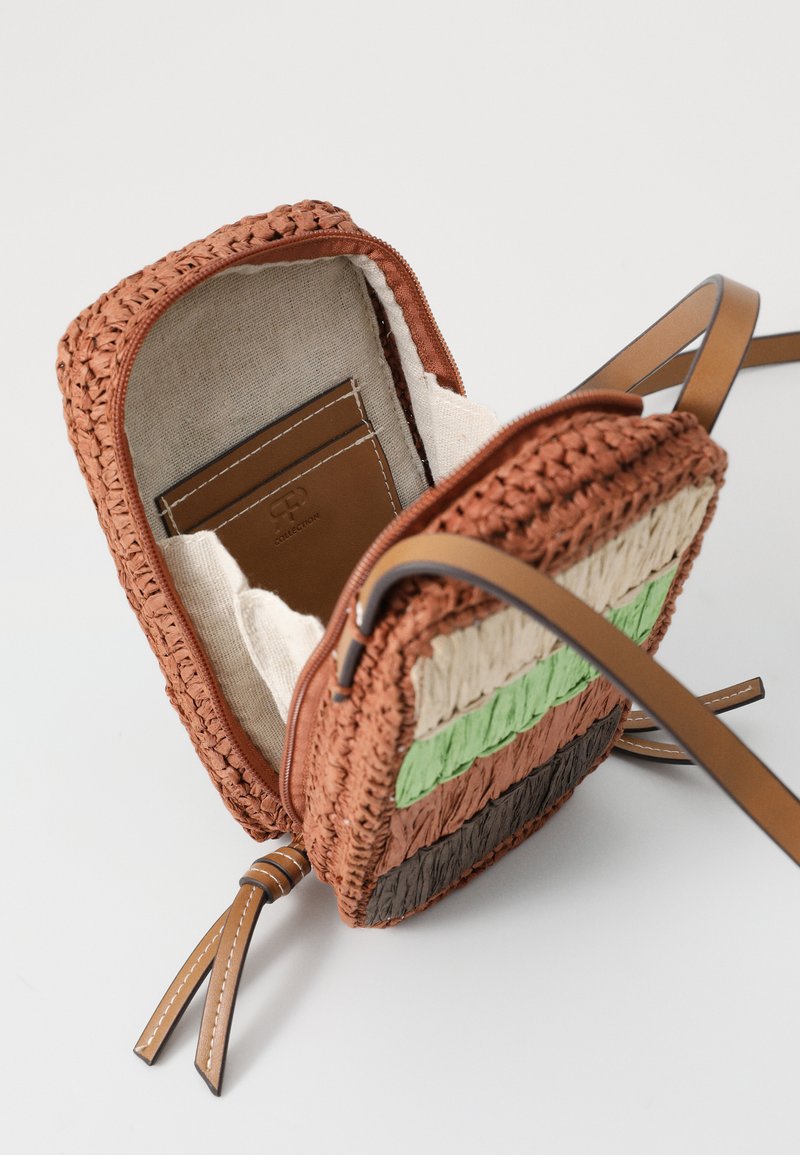 Bolso de mano tejido en naranja, verde, beige y marrón. Cuenta con un cierre de cremallera, asas de cuero en tono marrón y un bolsillo interior para tarjetas.