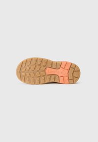 Brun gummiydersål med dybe spor for traction, prydet med en orange detalje og præget logo. Textureret overflade for greb.