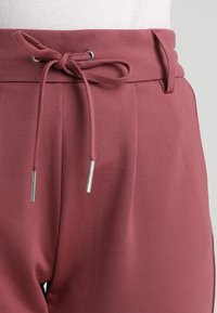 Roze gekleurde broek met een verstelbare tailleband, voorzien van zilverkleurige metalen uiteinden en een soepele, lichte stof. Aansluitend, ontspannen fit met plooien.