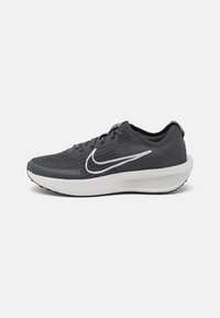 Chaussure de sport pour homme avec une tige en mesh gris foncé, un logo Nike blanc, une semelle intermédiaire blanche rembourrée et une semelle extérieure en caoutchouc noir texturée.