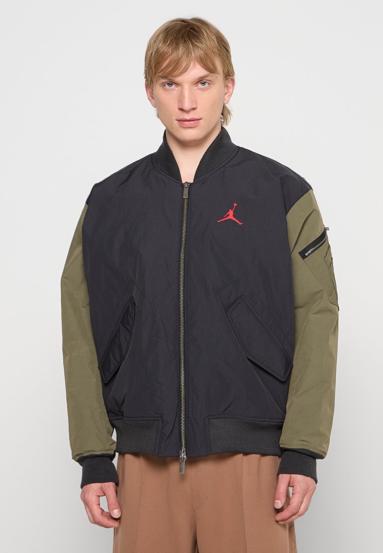 Schwarze und olivgrüne Bomberjacke, mit Reißverschluss vorne, gerippten Bündchen und Saum, mit rotem Logo-Akzent, Seitentaschen und strukturiertem Stoff.