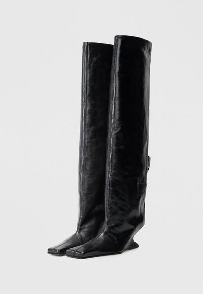 Czarne skórzane kozaki do kolan o eleganckim fasonie, z kwadratowymi noskami, teksturowaną powierzchnią i subtelnym srebrnym detalem po boku.