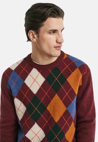Bordeaux argyle trui met diamantenpatronen in beige, groen, blauw en oranje. Ronde halslijn en zachte textuur.