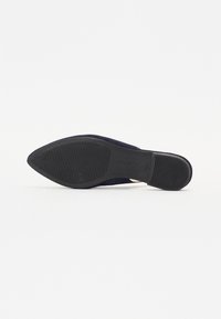 Zapato plano azul marino con suela texturizada negra, puntera afilada y parte superior de material liso. Diseño minimalista sin hardware ni acentos visibles.