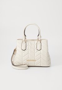 Crème handtas met gequilt patroon en chevron-design, dubbele handvatten en een afneembare schouderband. Bevat gouden branding en zwarte accenten.