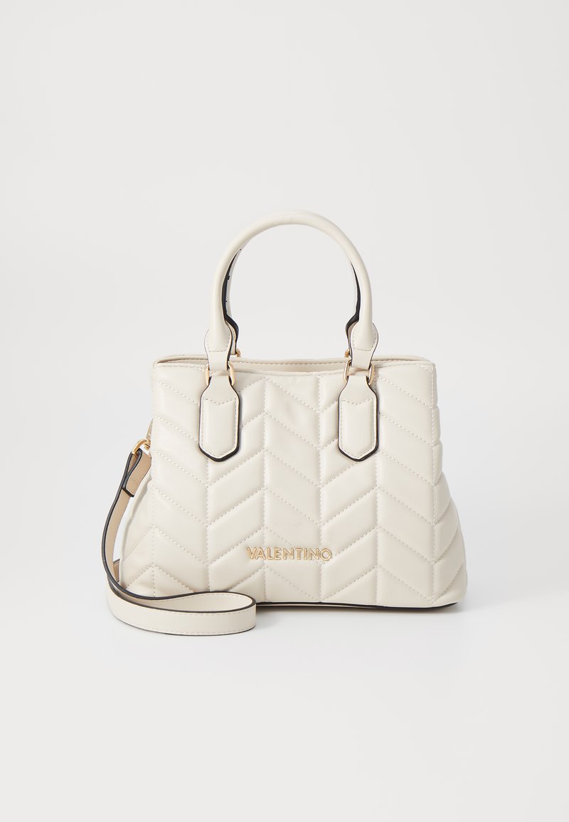 Cream quilted handbag with chevron pattern, dual handles, and detachable shoulder strap. Features gold-tone branding and black accents.