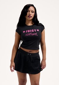 Fekete crop top rózsaszín "JUICY Angel" felirattal és szívekkel. Fekete szoknyával párosítva, amely elasztikus derékpánttal és húzózsinórral rendelkezik.