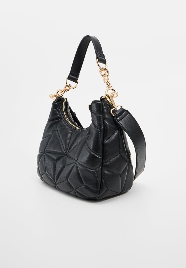Bolso de mano de cuero negro con un diseño acolchado, cuenta con un acento de cadena en tono dorado, un asa corta y una correa para el hombro removible. Cierre de cremallera.