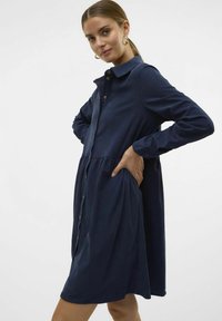 Marineblauw hemdjurk met een kraag, lange mouwen en een gelaagde rokdesign. Gemaakt van zachte stof, met zijzakken.