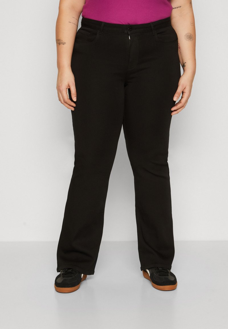 Pantalones negros con un diseño de pierna recta, fabricados con una tela suave, que presentan dos bolsillos frontales y un cierre de botón. Los zapatos son negros con suelas marrones.
