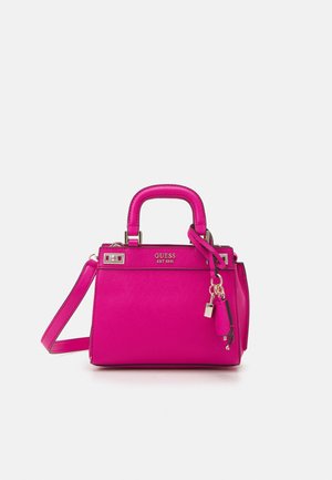 Bright pink Guess handbag with top handles, adjustable shoulder strap, and gold-tone lock and key charm on a white background.