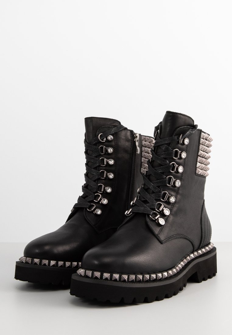 Stivali alla caviglia in pelle nera con suola spessa, borchie metalliche sul tallone e lacci decorativi con accessori e anelli in argento.