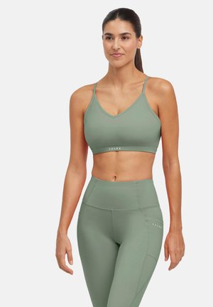 Lichtgroene sportBH met dunne schouderbandjes en V-halsontwerp, gecombineerd met hooggesneden leggings, met een gladde textuur en logodetail.