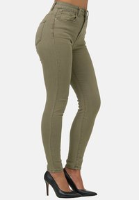 Jeans ajustados verde oliva con cintura alta, cierre de cremallera y botón, dos bolsillos traseros y una textura de tela suave y elástica.