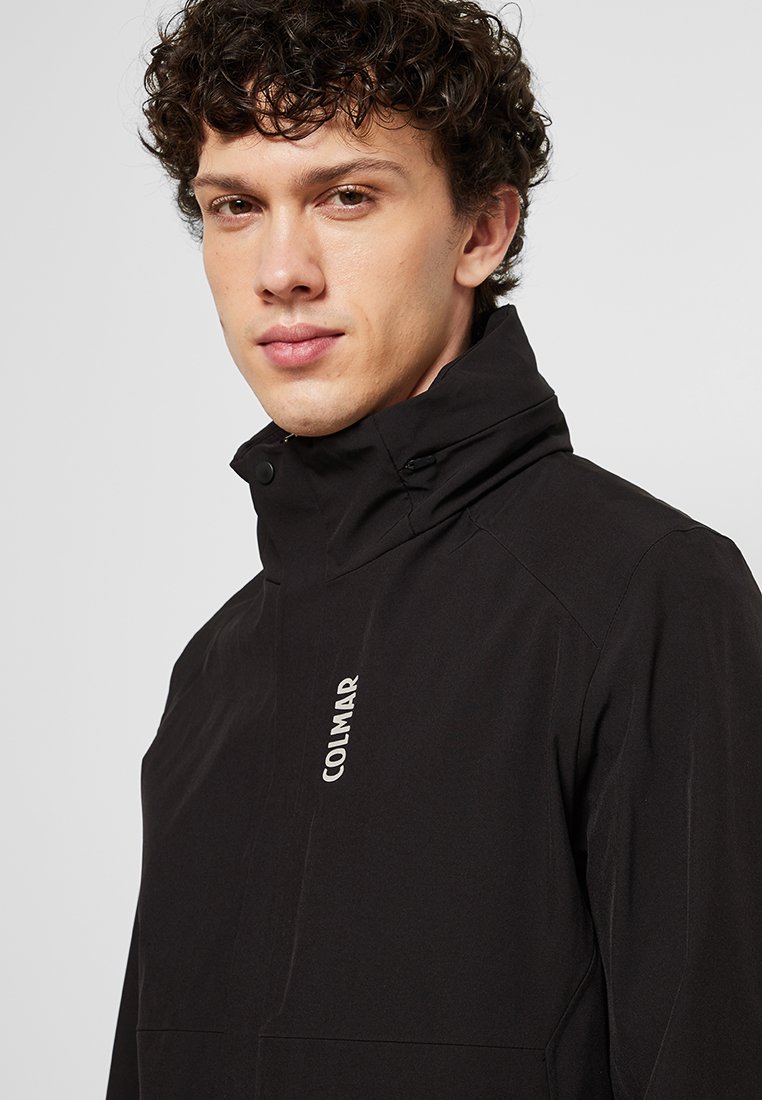 Giacca nera con colletto alto, chiusura a zip e logo sul petto. Tessuto morbido con cuciture minime, adatta per l'uso all'aperto.