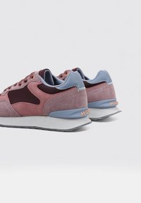 Sneakers med en överdel i rosa och burgundy mocka, ljusblå detaljer och grå gummisula. Har runda snören och varumärke på hälen.