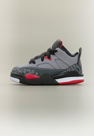 Γκρι, μαύρο και κόκκινο χαμηλό sneaker με μαύρες κορδόνια, διακοσμητικά μοτίβα και λευκή-κόκκινη σόλα σε ουδέτερο φόντο.