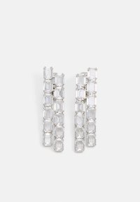 Boucles d'oreilles rectangulaires transparentes au design en cascade, présentant plusieurs pierres reliées, montées en métal argenté avec une finition polie.